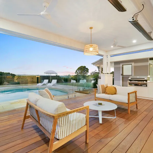Outdoor area featuring new decking, glass balustrading, and an outdoor cooking area, seamlessly connecting home to the swimming pool